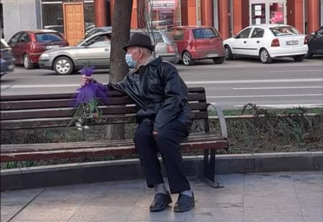 Imagine virală! Un bătrân îmbărcat elegant, ține un buchet de flori în mână în așteptarea femeii iubite