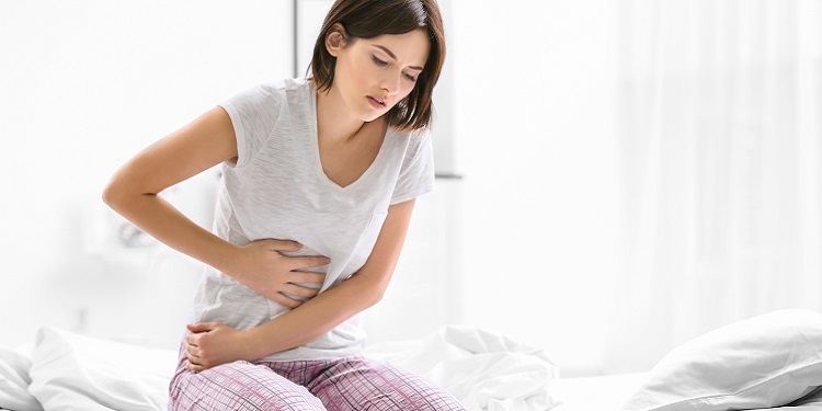 femeie care se tine de burta din cauza durerii provocate de diaree