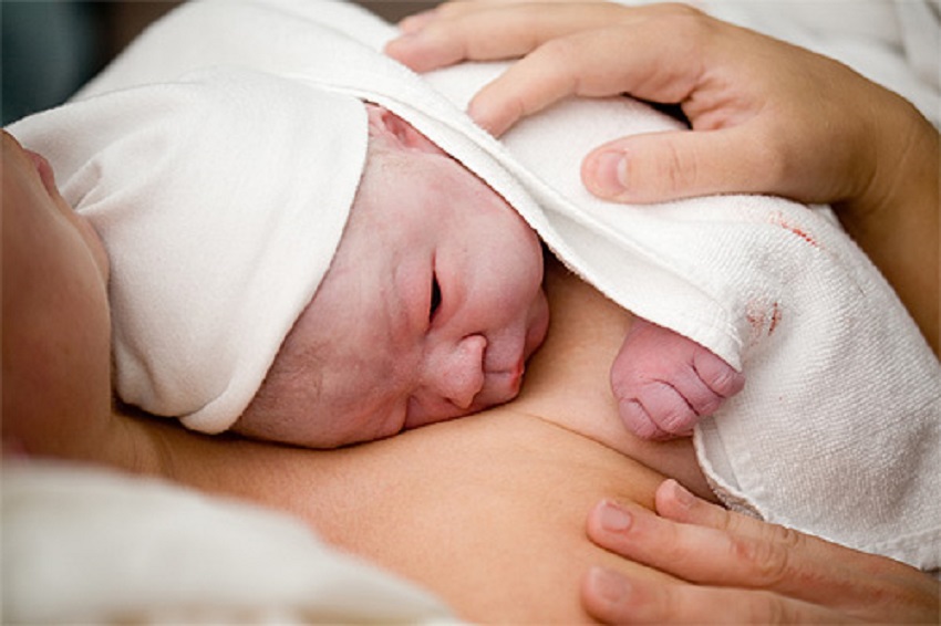 un bebeluș ținut în brațe de mama sa