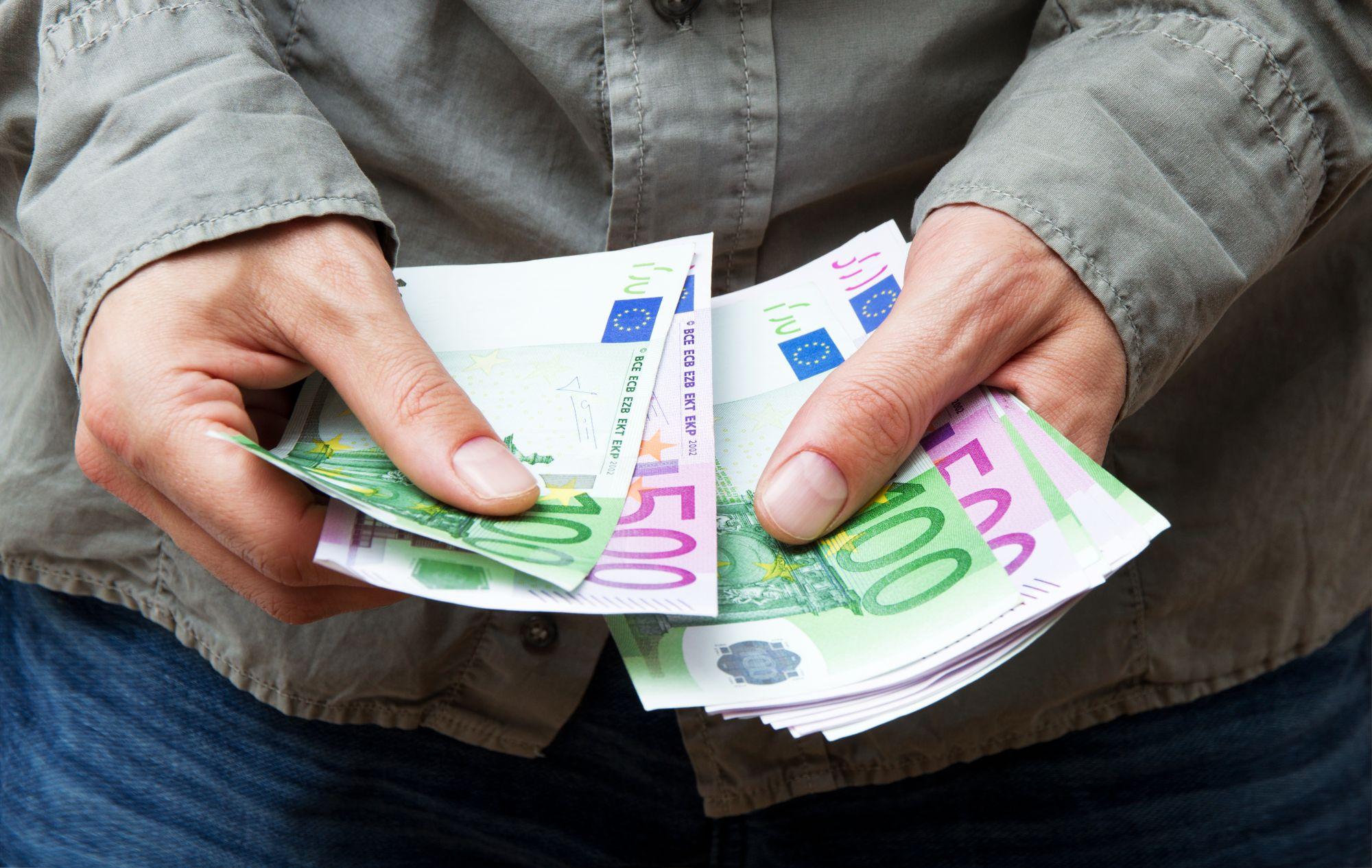 mai multe bancnote euro tinute in mana