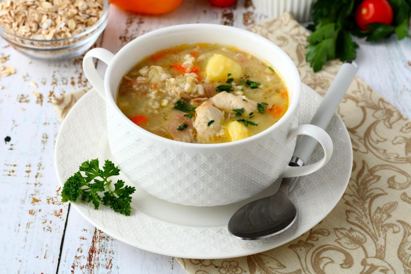 peasants soup on a plate next to a spoon on a table