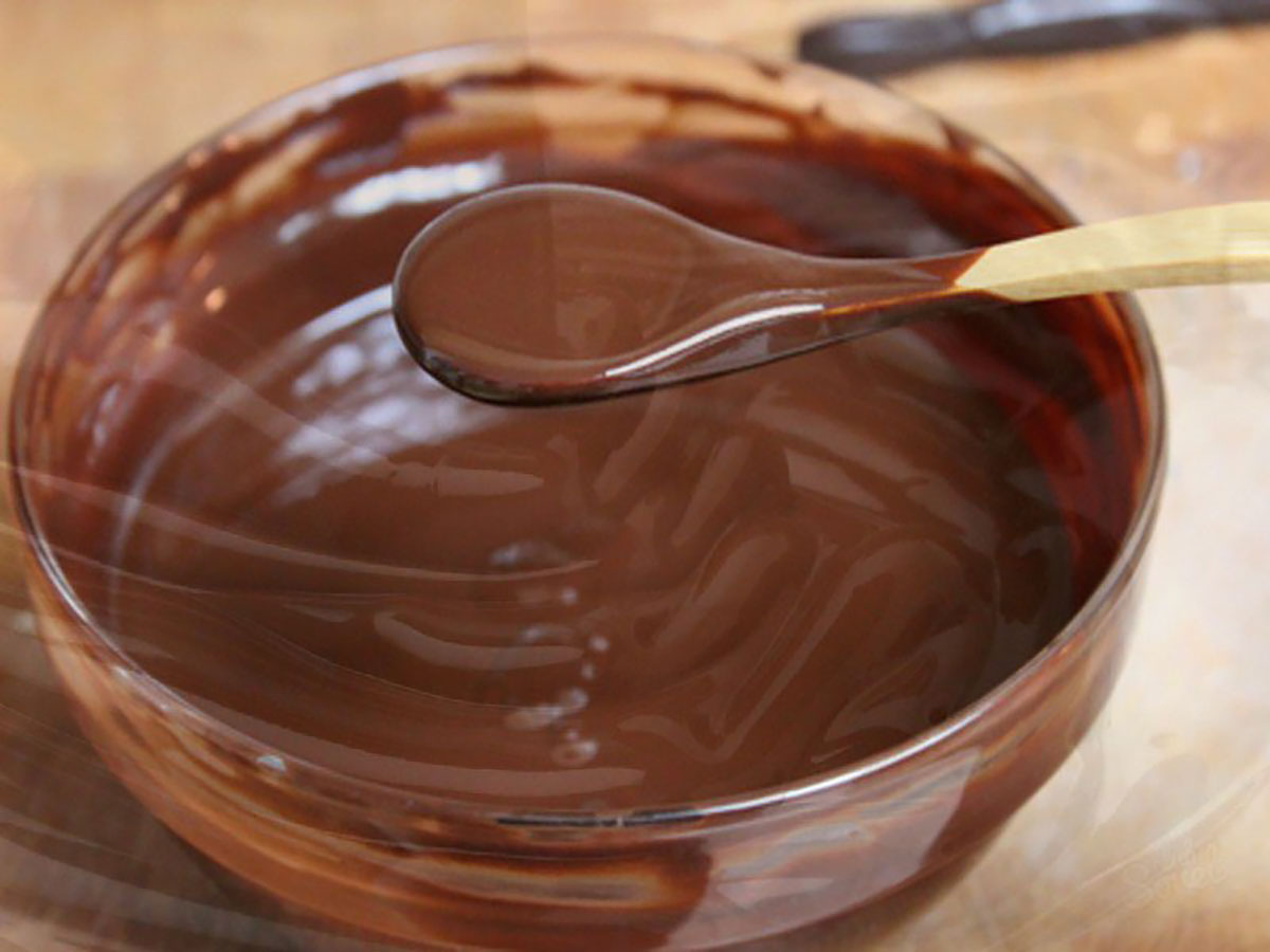o lingura de lemn cu glazura peste un vas cu ciocolata