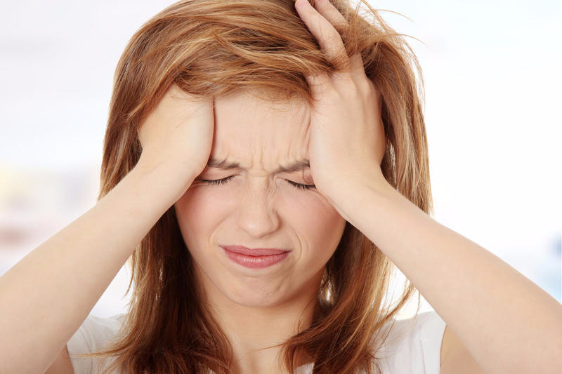 femeie care se tine de cap din cauza migrenei