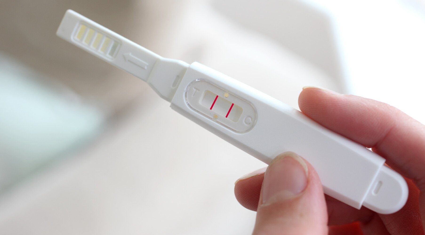 femeie care tine un test de sarcina in mana