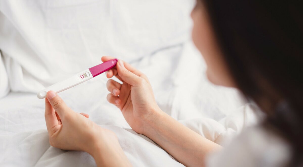 femeie care priveste un test de sarcina pozitiv