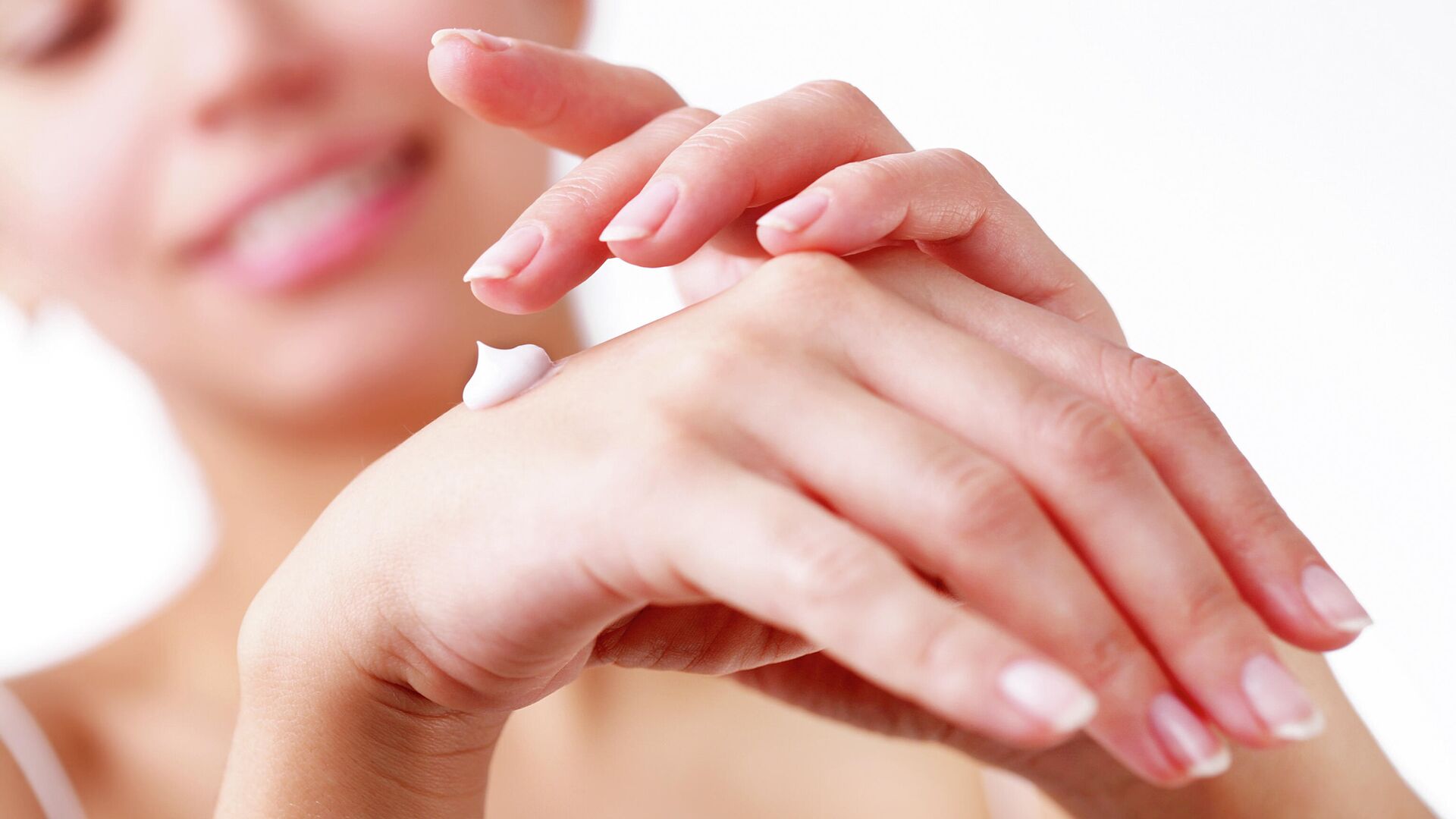 femeie care aplica o crema pe maine pentru hidratarea pielii uscate
