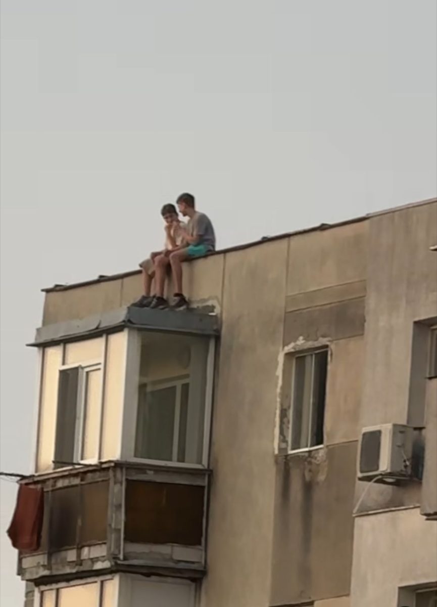 Inconștiență dusă la extrem. Doi copii au fost fotografiați pe acoperișul unui bloc de 10 etaje din Alexandru cel Bun. Au picioarele pe exterior