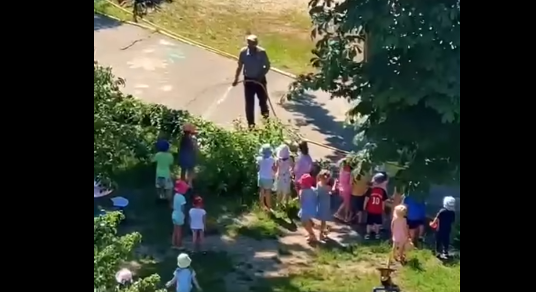 Moment adorabil devenit viral! Un bărbat stropește cu furtunul zeci de copii într-o grădină, pentru a-i amuza